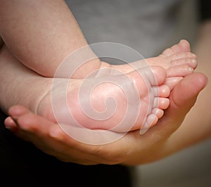 Feet of newborn baby in the hand of mother