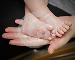 Feet of newborn baby in the hand of mother