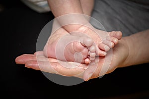 Feet of newborn baby in the hand of mother