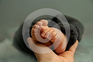 Feet of newborn baby in hand of mother, tiny toes of infant baby in a selective focus