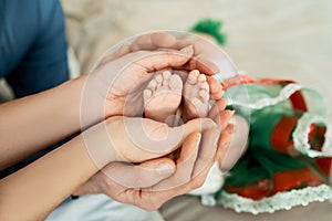 Feet of a newborn baby in the hands of parents. Happy Family oncept. Mum and Dad hug their baby`s legs