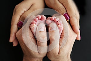 Feet of newborn baby in the hands of parents. Happy Family oncept. Mum and Dad hug their baby& x27;s legs