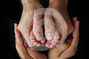 Feet of newborn baby in the hands of parents. Happy Family oncept. Mum and Dad hug their baby& x27;s legs