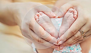 Feet of a newborn baby in mom's hands. Selective focus