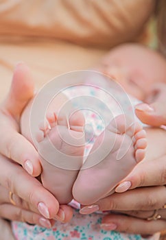 Feet of a newborn baby in mom's hands. Selective focus