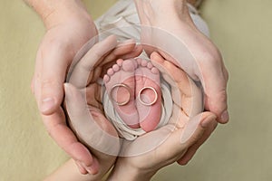 Feet of a newborn baby, toes in the hands of mom and dad,   the first days of life after birth, family wedding rings
