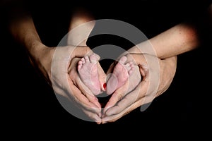 Feet of a newborn in the hands of parents