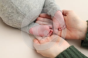 Feet of the newborn on the palms of the parents. Studio macro photo of child& x27;s toes, heels and feet