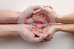 Feet of the newborn on the palms of the parents. Studio macro photo of child& x27;s toes, heels and feet