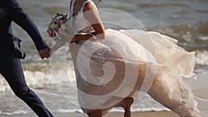Feet of the newlyweds running barefoot at the seaside after wedding ceremony. Bride's, groom's legs at sandy