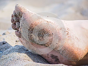 Feet of one unrecognizable caucasian person resting in sand