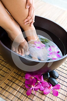 Feet in oriental foot bath with flowers