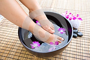 Feet in oriental foot bath with flowers