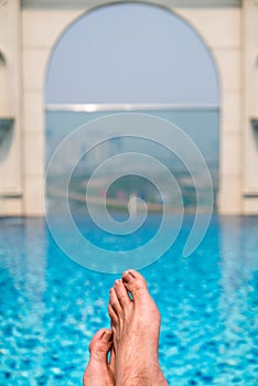 Feet over the sparkling pool on top of building with Saigon aerial view