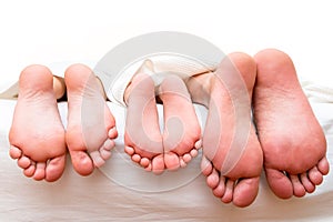 Feet of parents and child on the bed