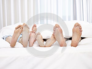 Feet of parents and children in bed