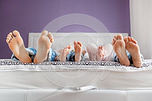 Feet of parents and children lying on the bed