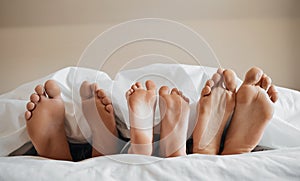 Feet, parents and kid sleeping on bed to relax with love, rest or sleeping on hotel mattress in morning. People