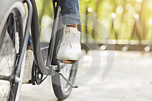 Feet On Pedals Of Unrecognizable Black Man Riding Bicycle In Park