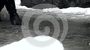 The feet of people walking on a snow-covered city street.