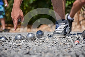 Petanque player pointing at the ground, holding a steel ball