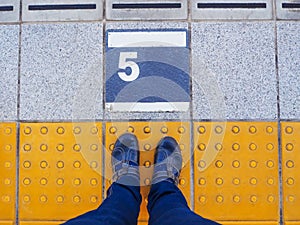 Feet on the platform number 5 at train station