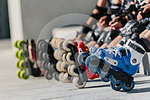 Feet of rollerbladers wearing inline roller skates sitting in outdoor skate park, Close up view of wheels befor skating