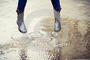 Feet in rubber boots in puddle