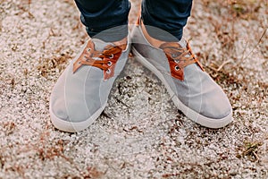 Feet in the sand. Hipster in cool sneakers.Top view of shoes on sand texture background