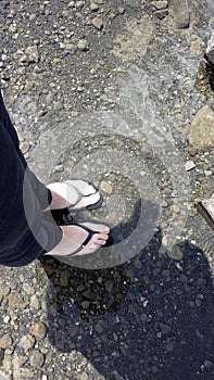 Feet in sandals and their shadow in the water of Ranco Lake