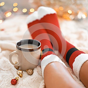 Feet in Santa`s socks near the Christmas tree