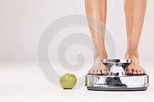 Feet, scale and apple in studio on a gray background with mockup for diet, weightloss or detox. Food, weightscale and