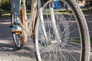 Feet shod in bright sneakers stand on the pedals