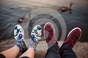 Feet with shoes of the couple on romantic date sitting on the rocks near lake