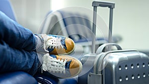 Feet and shoes of a young hipster passenger taking nap near the gate while waiting for connection or delayed flight