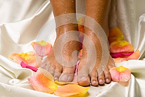 Feet on the silk cloth with rose-petals