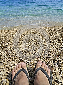 Feet in slippers on pebble beach