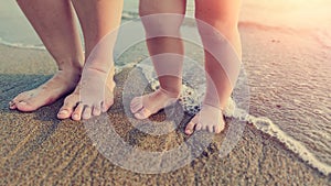 Feet small baby  on the sand with water wave of the sea beach