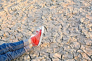 Feet sneaker on crack dry ground