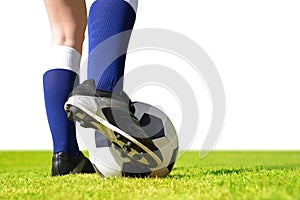 Feet of soccer player with ball on football field.