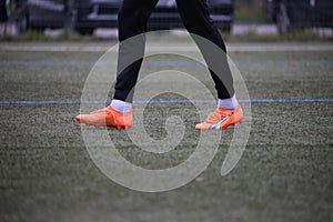 the feet of a soccer player in orange and black shoes