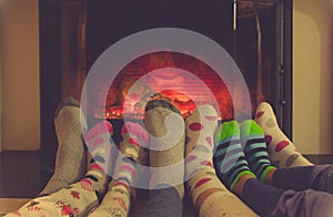 Feet in socks of all the family warming by cozy fire