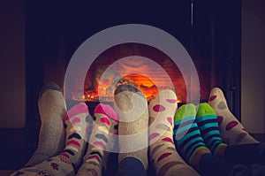 Feet in socks of all the family warming by cozy fire photo