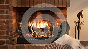 Feet in socks in front of the fire of a fireplace in winter.