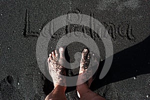 Feet standing on a black sand beach of La Palma