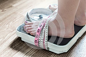 Feet tied up with measuring tape to a weight scale