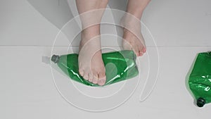 Feet trample on plastic bottles for disposal. The concept of helping the environment from pollution with garbage