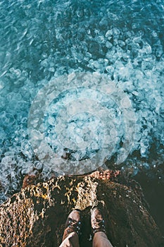 Feet traveler boots standing at the edge above sea full of Jellyfish in water