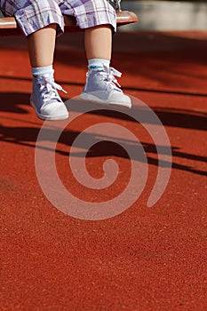 Feet of a little child swinging on playground