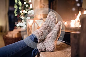 Feet of unrecognizable woman in socks by the Christmas fireplace